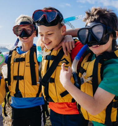 Three boys wearing life vests and snorkels in preparation for the snorkeling activity at Fairbridge's School Camp