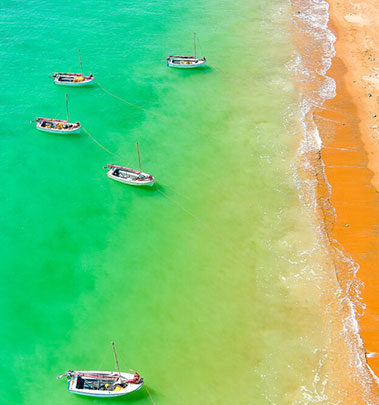 An aerial view of Camp Fairbridge's ocean, showcasing five boats ready to sail at the school camp
