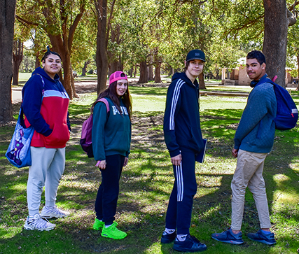 Four people wearing jackets stand in front of tall trees, ready for training at Fairbridge's School Camp