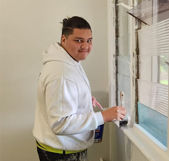 Levi, an apprentice in Fairbridge school camp, applies paint to a window, showcasing creativity in Pinjarra Fairbridge